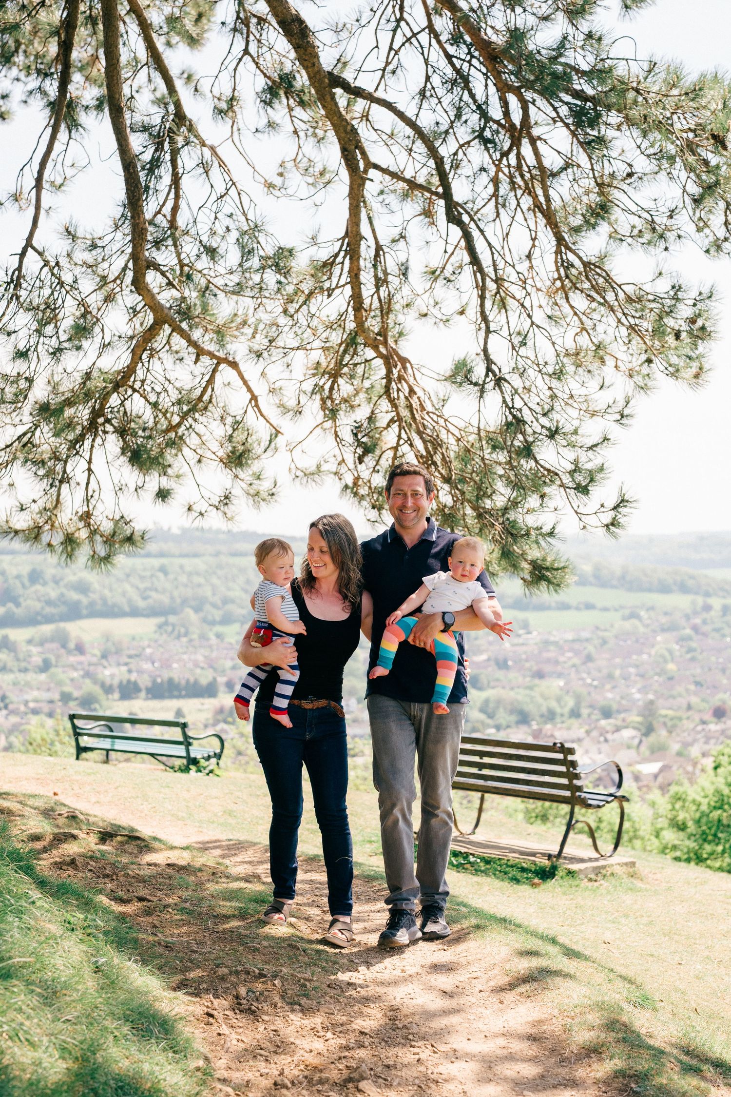 Documentary family photography showing parents standing outdoors with their young children during a relaxed countryside.