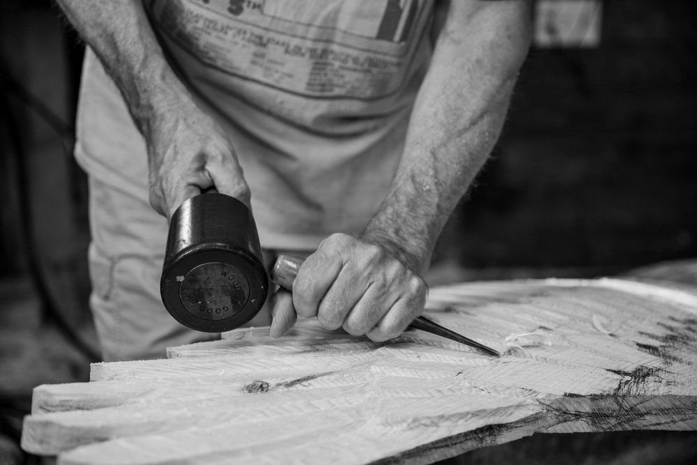 Close-up view of hands rolling out dough on a floured wooden surface with a rolling pin.