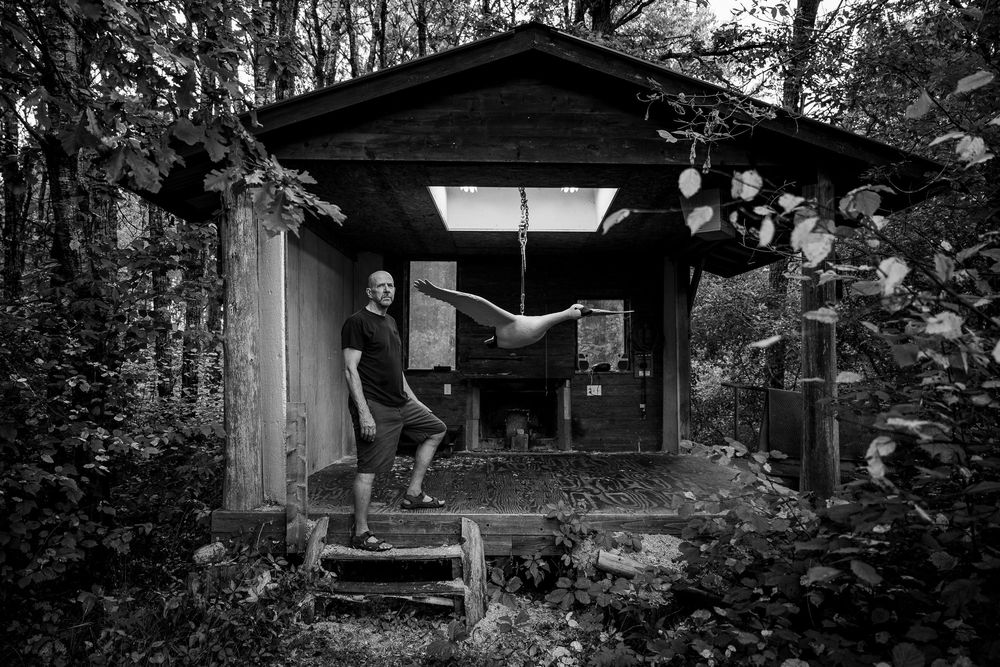 A row of rustic wooden cabins nestled among tall trees in a black and white forest setting.
