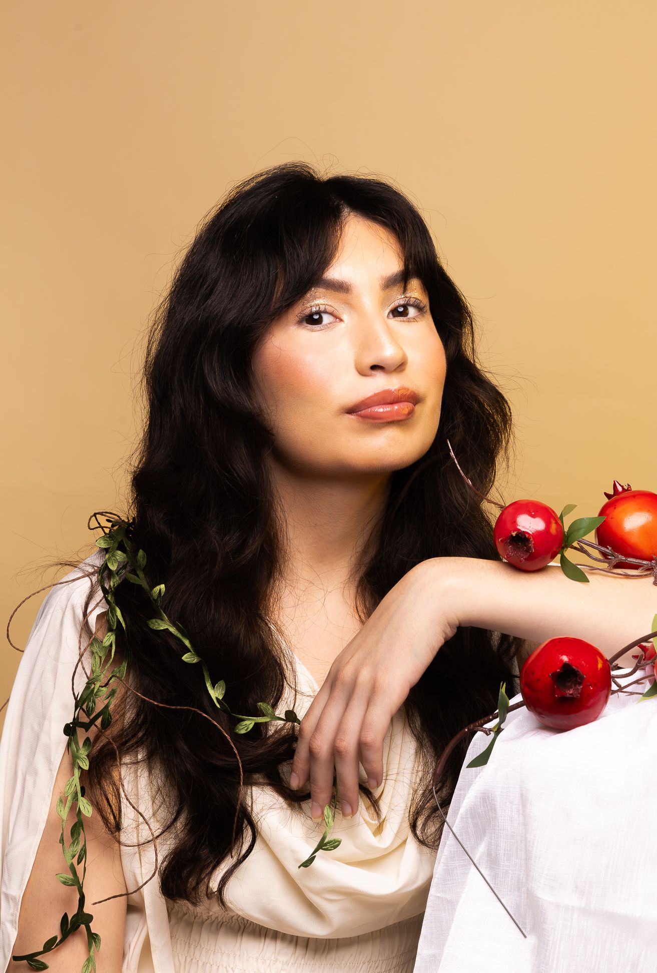 Persephone, Goddess of Spring Growth & Queen of the Underworld, girl sitting with pomegranates and vines looking straight - close up shot