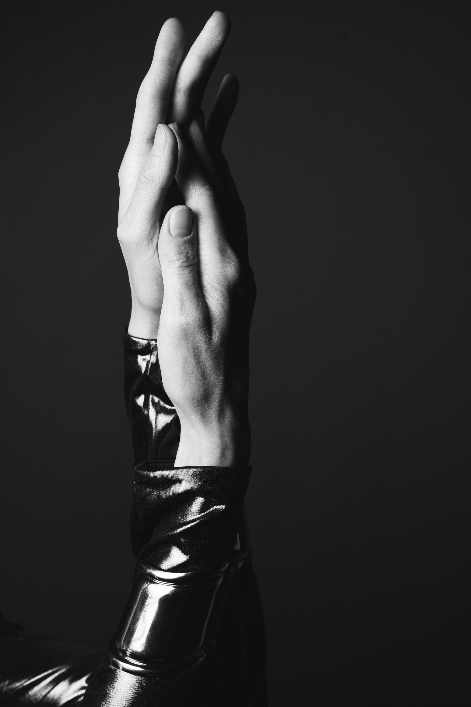 black and white photograph of two female hands clasped together in a shiny dress taken in a studio in King's Lynn