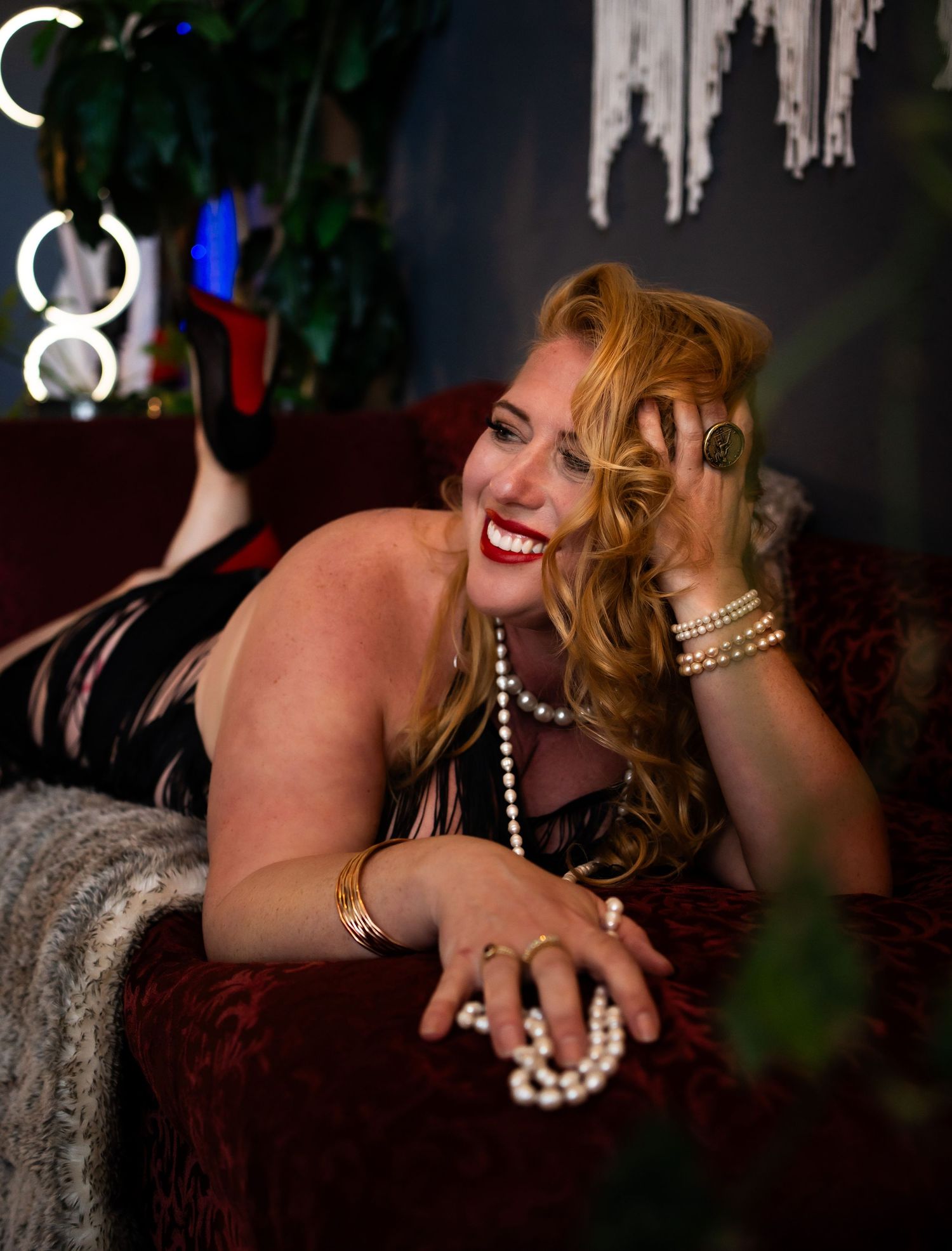 A sequence of glamour photos showing someone wearing pearl necklaces and jewelry while posing on a couch.
