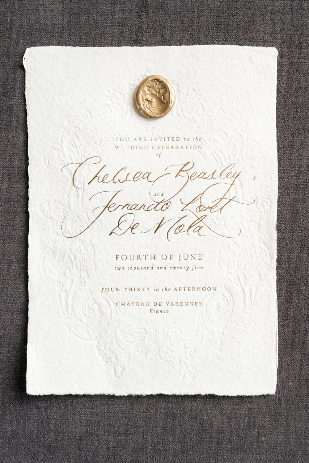Elegant wedding invitation on textured white paper with gold wax seal and calligraphy text for a June celebration.
