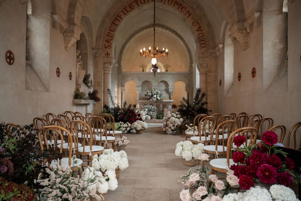 Elegant wedding reception setup in a white stone castle ballroom with crystal chandeliers and floral centerpieces.