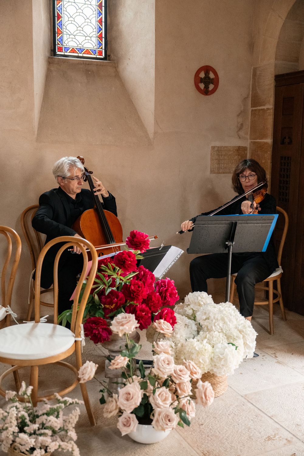 String musicians perform at an elegant event with pink and white floral arrangements in the foreground.