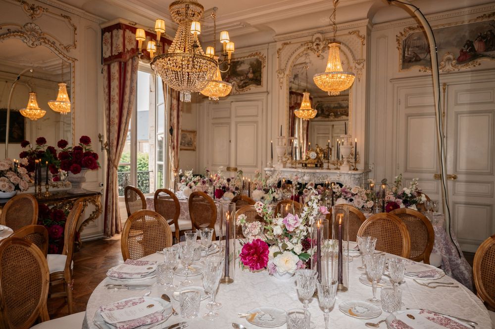 Elegant dining room with crystal chandeliers and ornate white walls set for a formal dinner party.