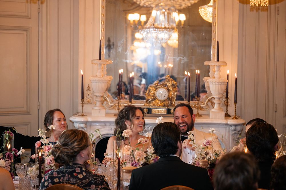 Guests seated at elegant tables with crystal chandeliers during a formal wedding reception in a grand ballroom.