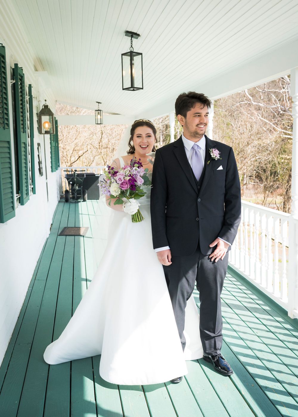 Wedding couple walks along a covered porch with green shutters casting geometric shadows.