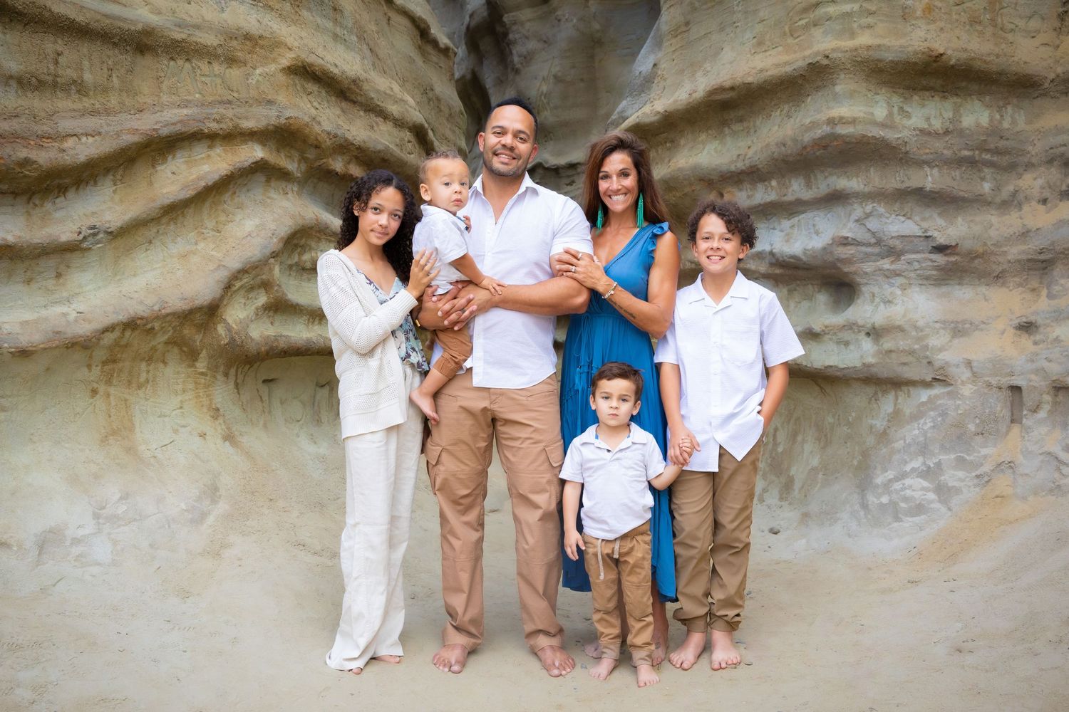 Group portrait against a textured rock wall backdrop in coordinated neutral outfits.