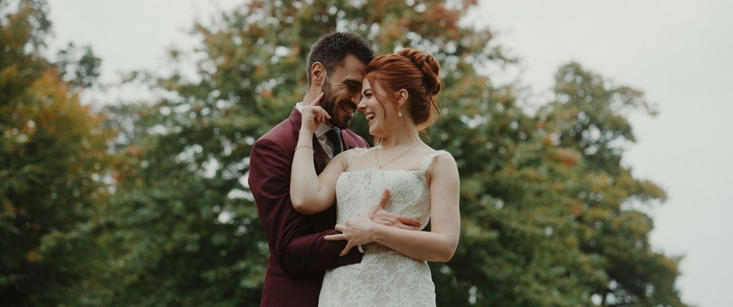 A romantic outdoor wedding scene with a couple embracing among autumn trees in the background.