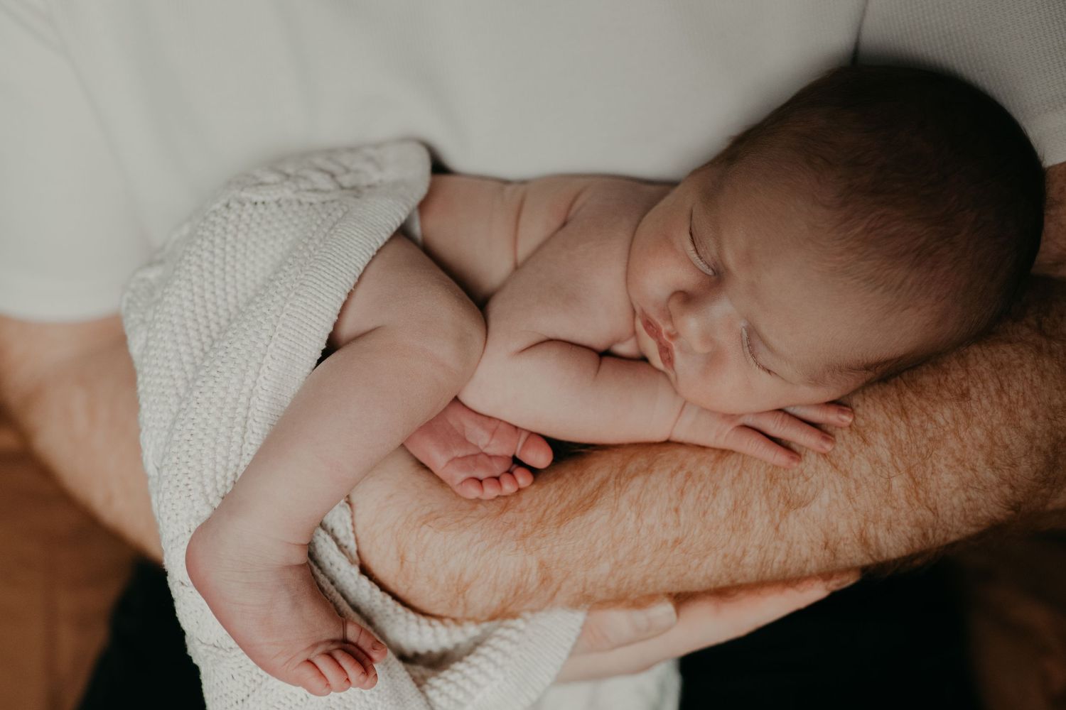 a new born baby sleeping on his father's arm