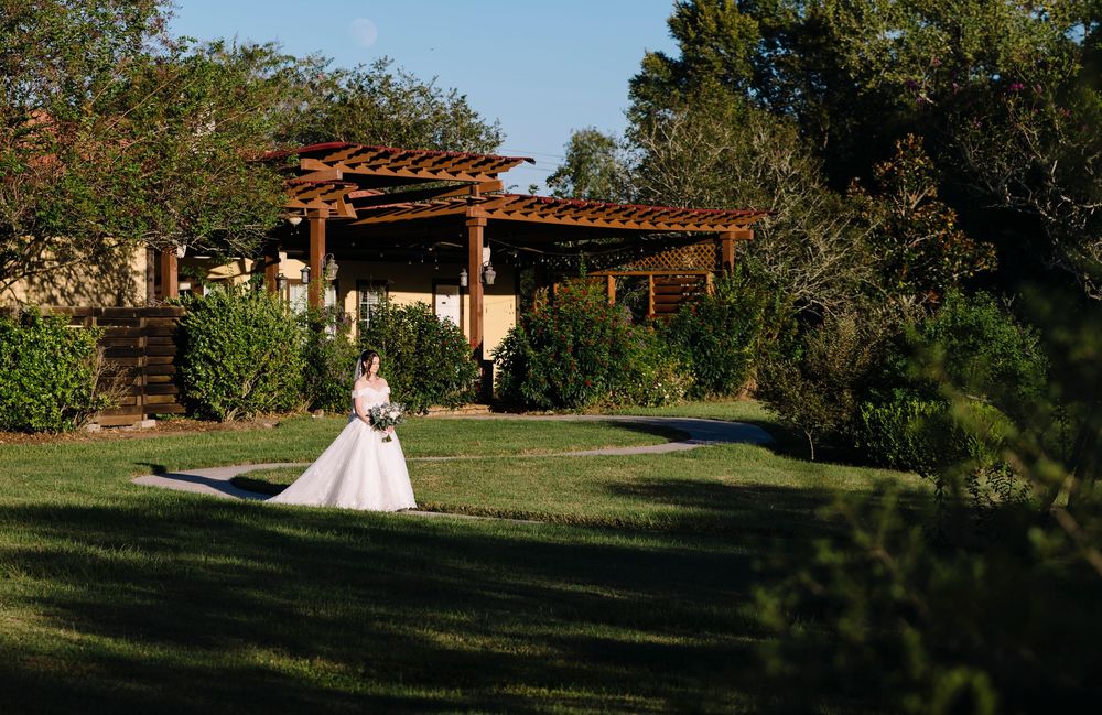 A panoramic view of a rustic outdoor wedding venue with wooden pergolas and lush green landscaping at sunset.