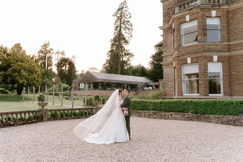 Worcestershire Newlyweds walk hand in hand along a gravel path outside Bredenbury Court Barns on their wedding day.