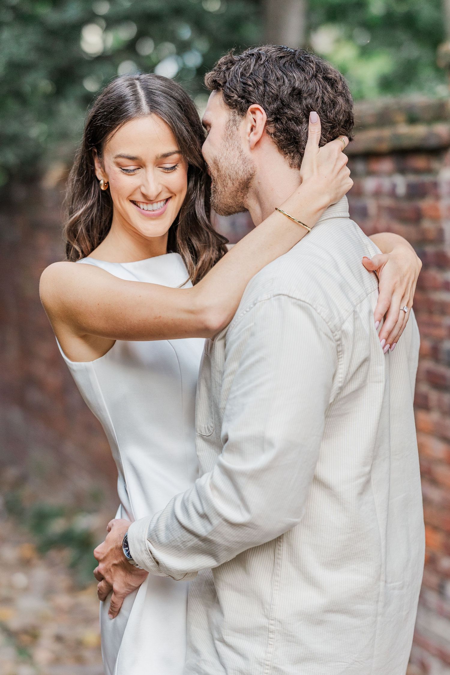 A romantic couple in white outfits share tender embraces and intimate moments during an outdoor photo session.