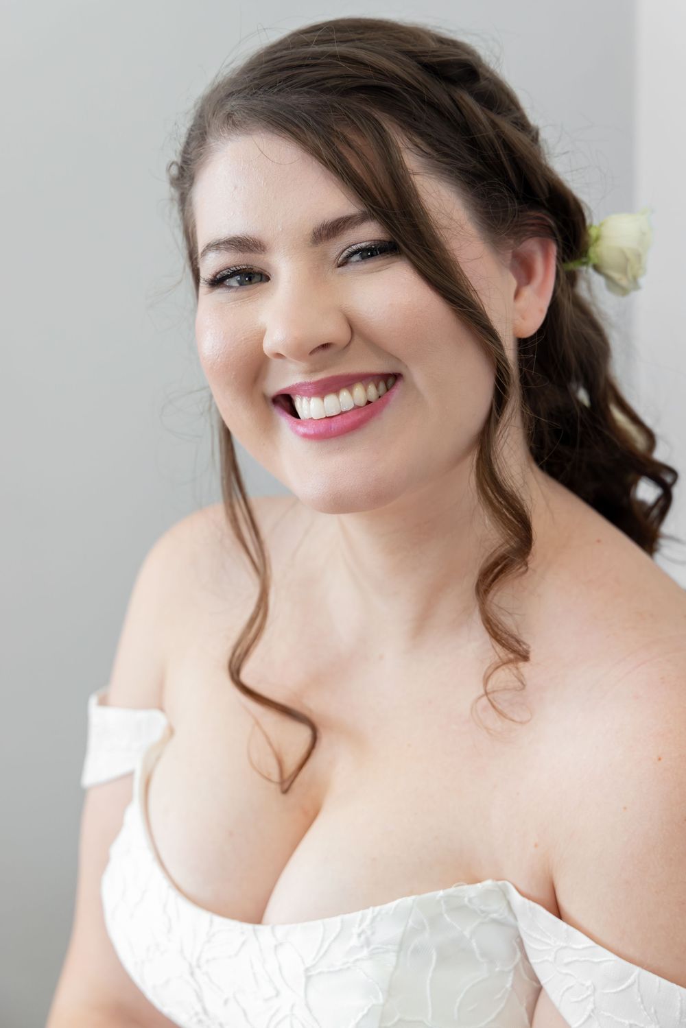 Close-up portrait showing a bright smile and soft curls against a light background.