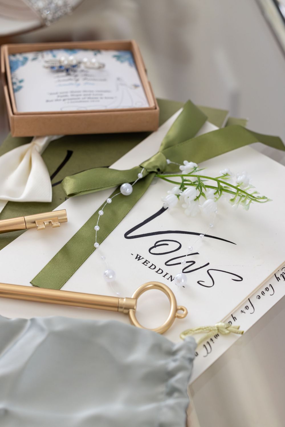 Wedding stationery with sage green ribbons and delicate floral details laid out on a light surface.
