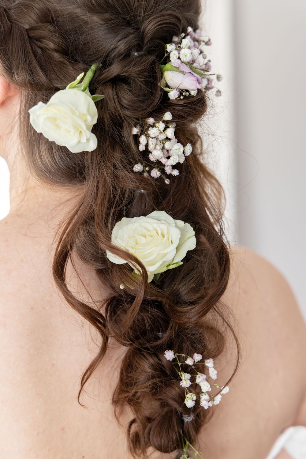 Romantic bridal hairstyle with white roses and baby's breath flowers woven into loose curls.