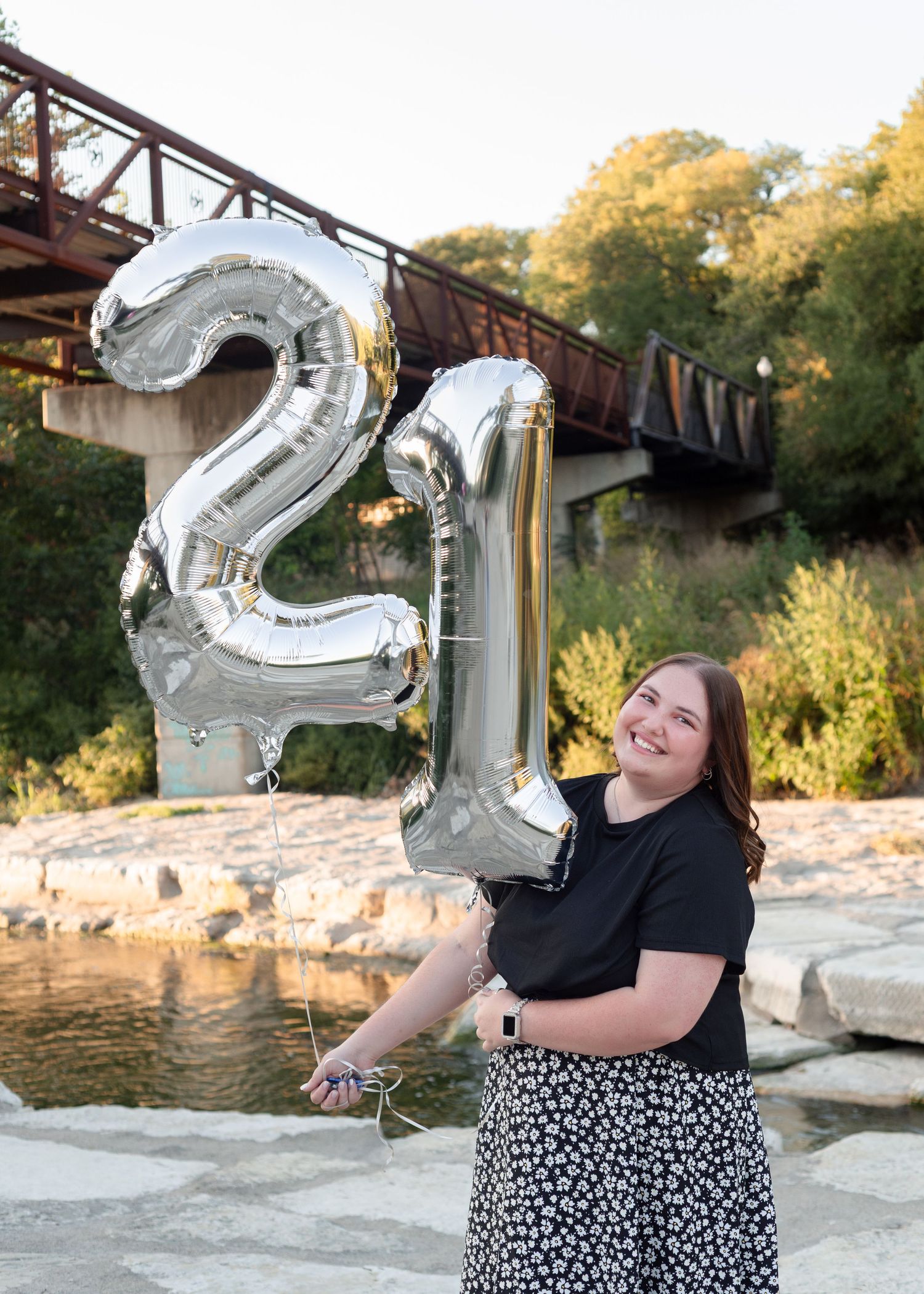 Woman holding balloons during birthday milestone session at Nolan Creek in Belton Texas