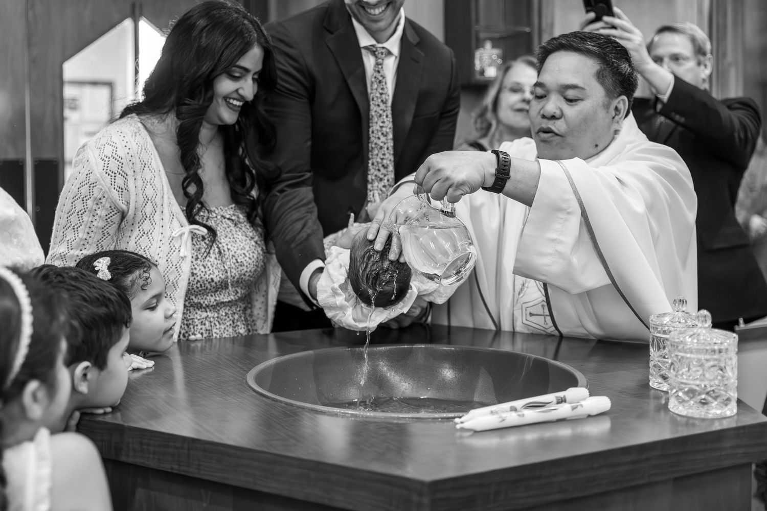 A series of black and white candid wedding reception photos showing guests laughing and enjoying themselves at tables.