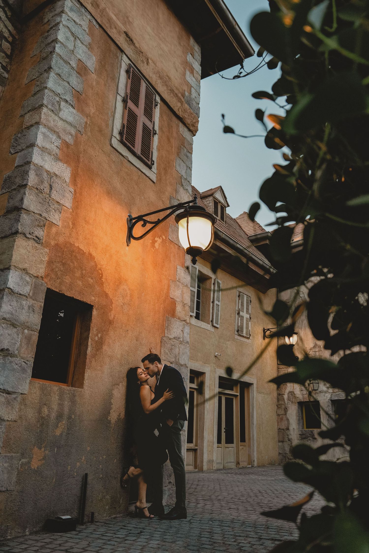 Romantic evening couple portrait beside warm-lit historic building at dusk Riverland Dubai
