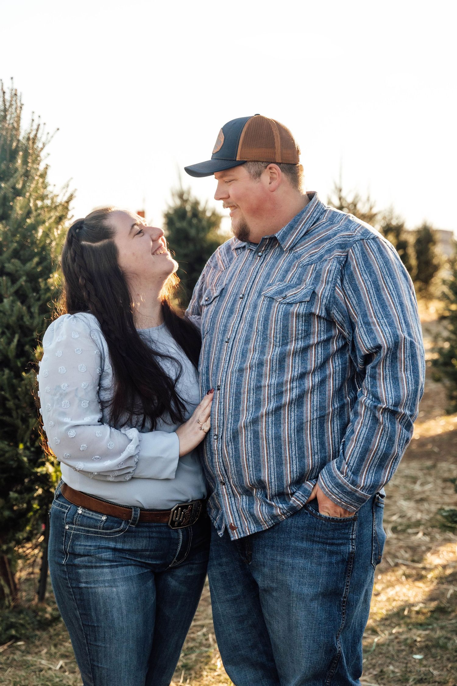 Casual couple in denim and plaid share playful moments outdoors at sunset.