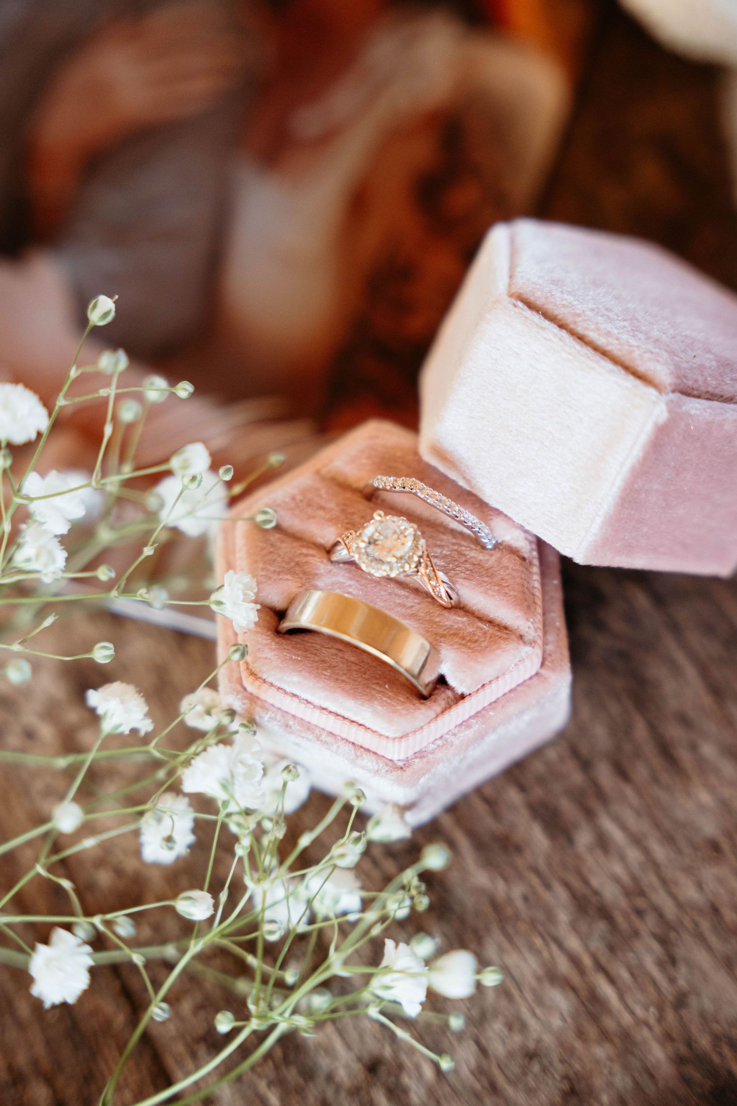 Close-up of rose gold engagement ring box with delicate baby's breath flowers.