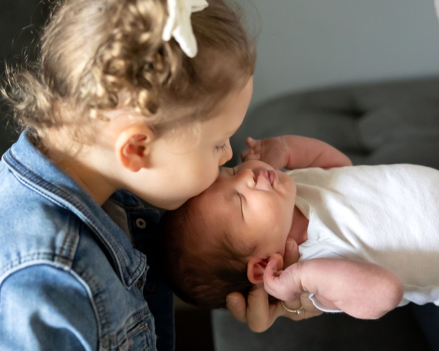 A series of five close-up shots showing a sweet moment of a child gently kissing a newborn baby.
