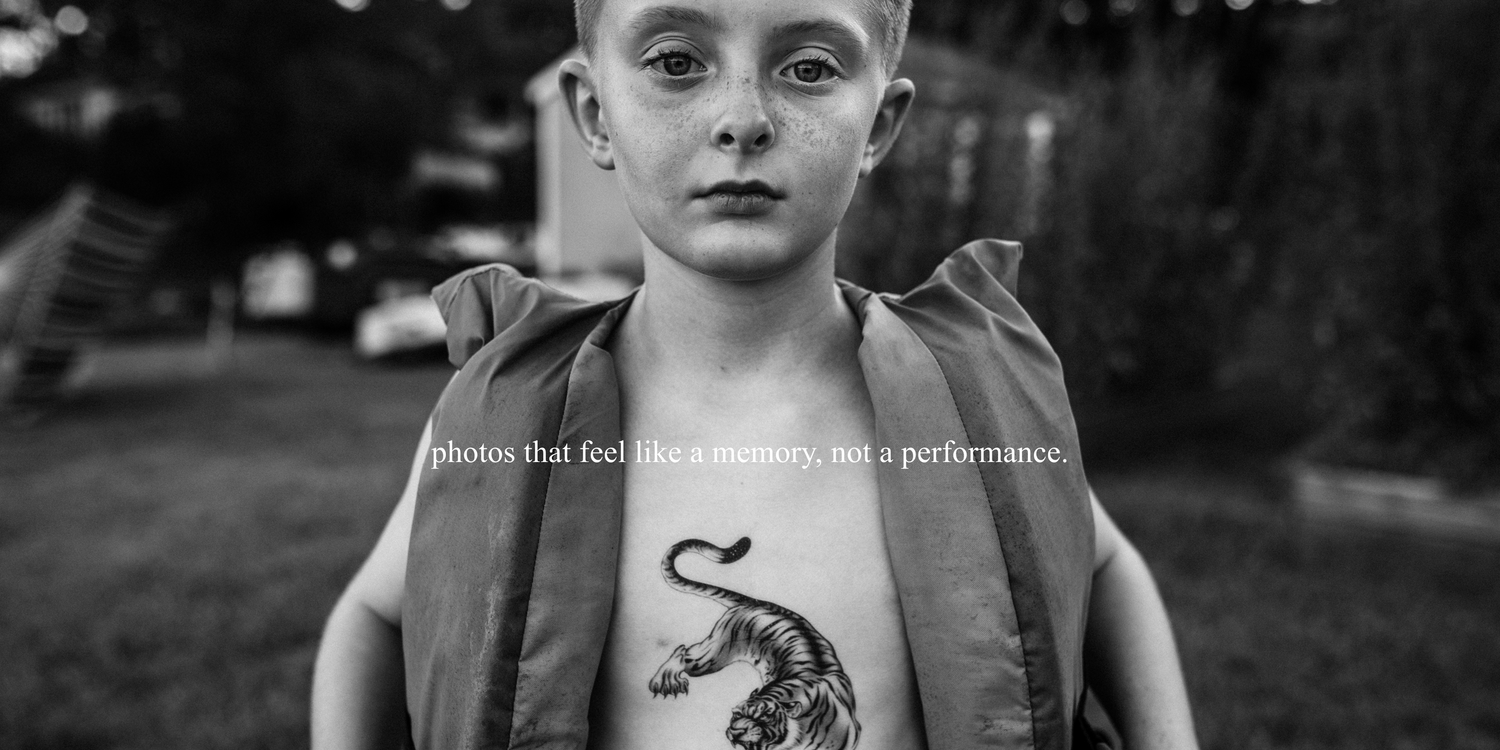 A black and white portrait photograph of a boy with a lifejacket on and tiger tattoo on his chest during at home family photo session