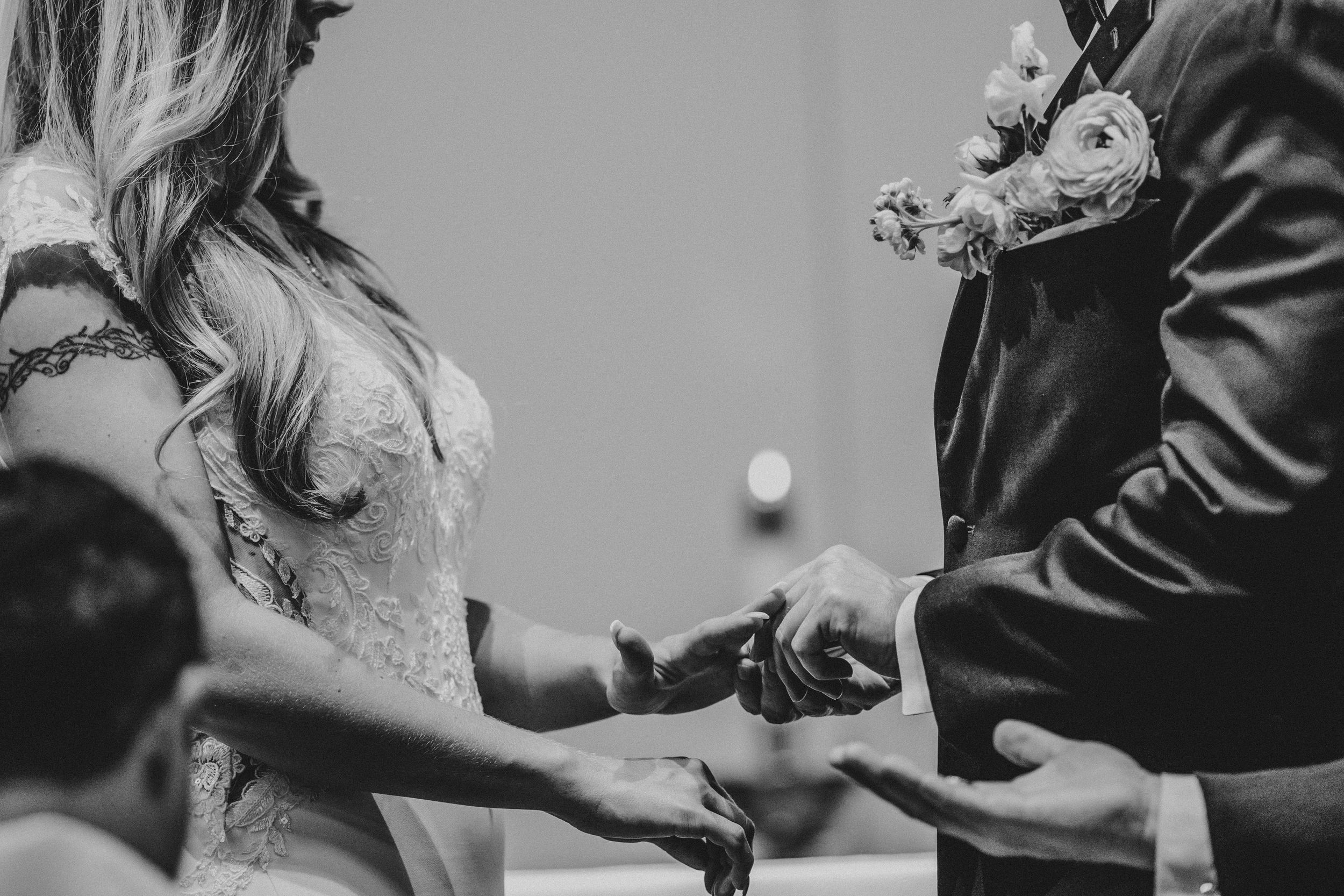 A series of black and white photos showing hands exchanging rings during a wedding ceremony.