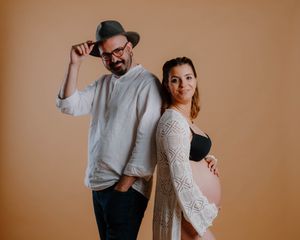 A couple embraces in a warm brown studio setting, creating intimate and romantic engagement portraits.