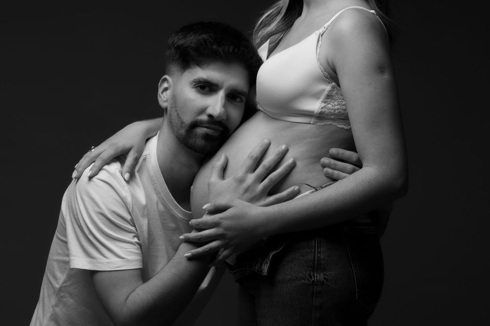 Black and white maternity photo showing hands tenderly cradling a pregnant belly.