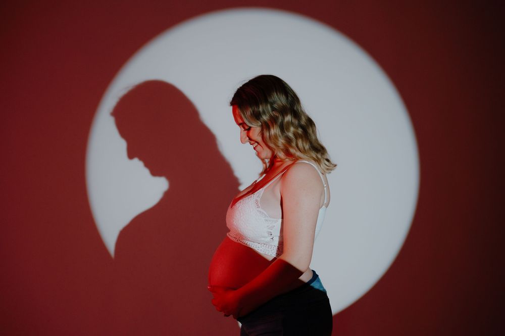 A dramatic silhouette series shows a woman in a flowing dress twirling and dancing against a dark red background.