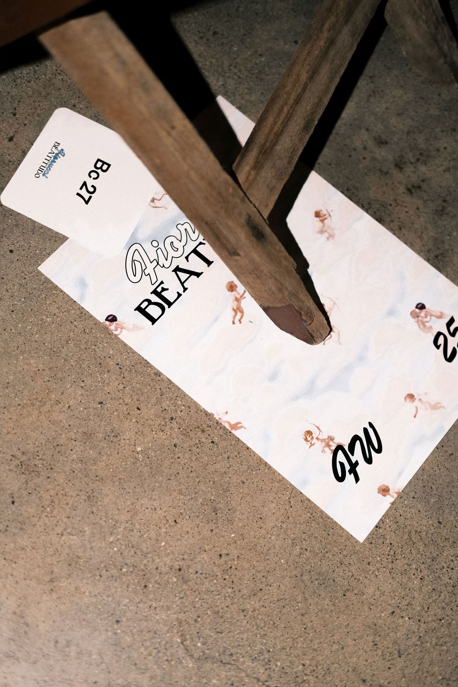 Several white paper tags with handwritten text lay scattered on a concrete floor surface.