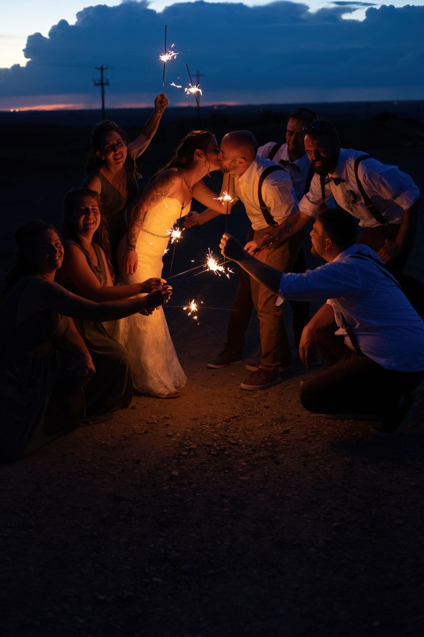 A group of people gather on a beach at dusk holding sparklers creating a magical nighttime atmosphere.