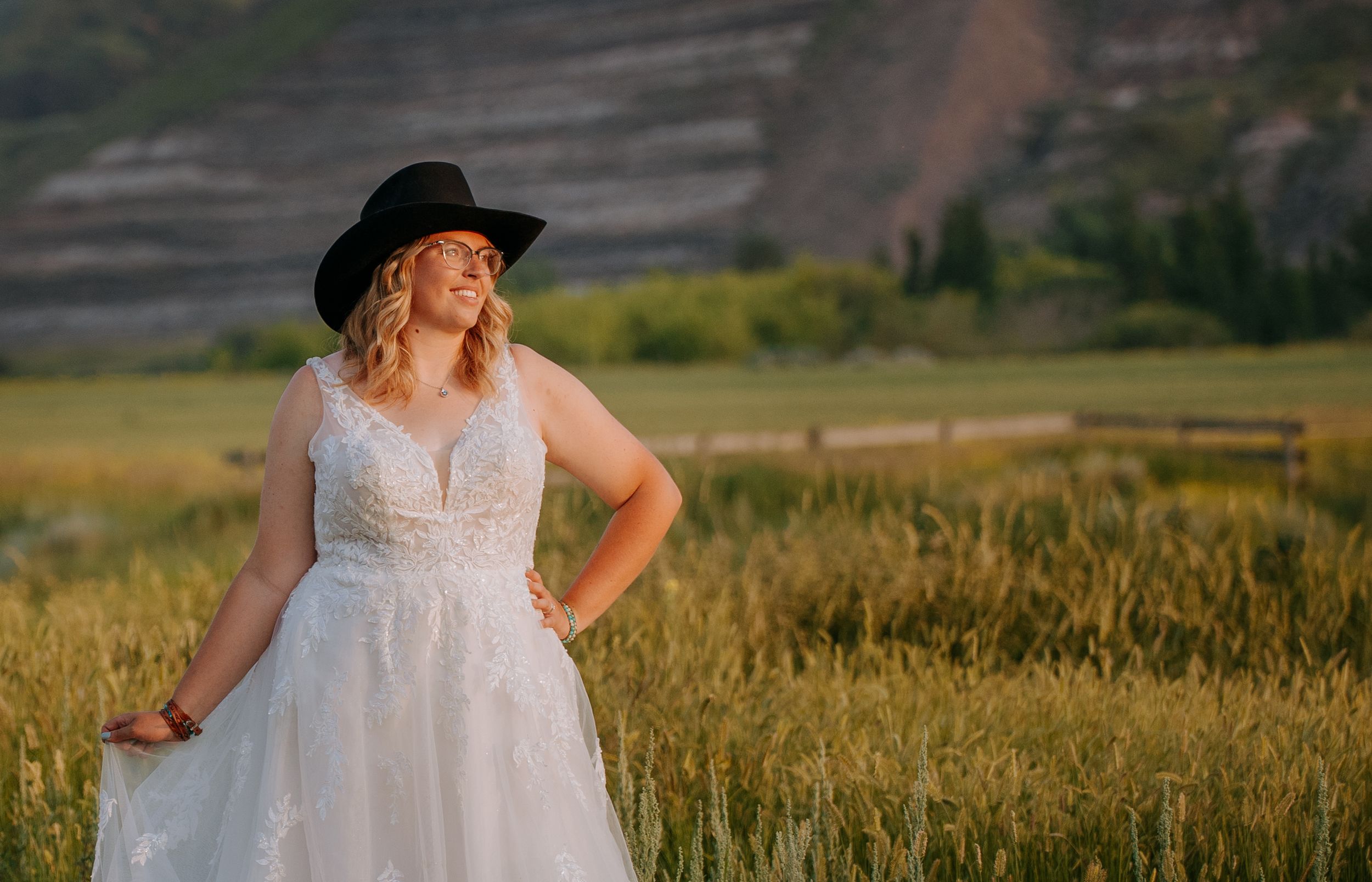 A couple in wedding attire stands in a golden wheat field during sunset creating a romantic silhouette.