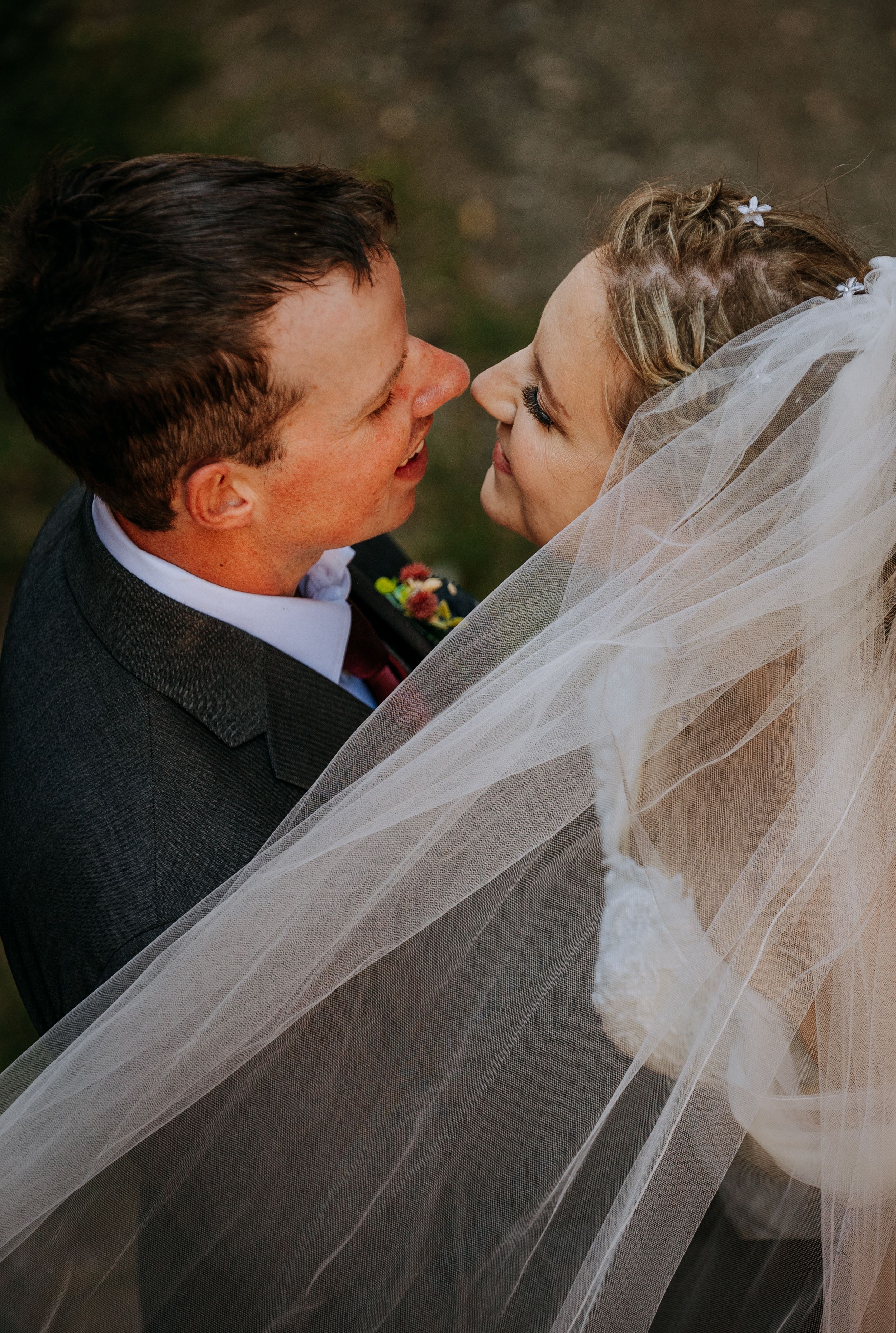 A romantic wedding moment captured in warm light with the bride's veil flowing as the couple shares an intimate moment.