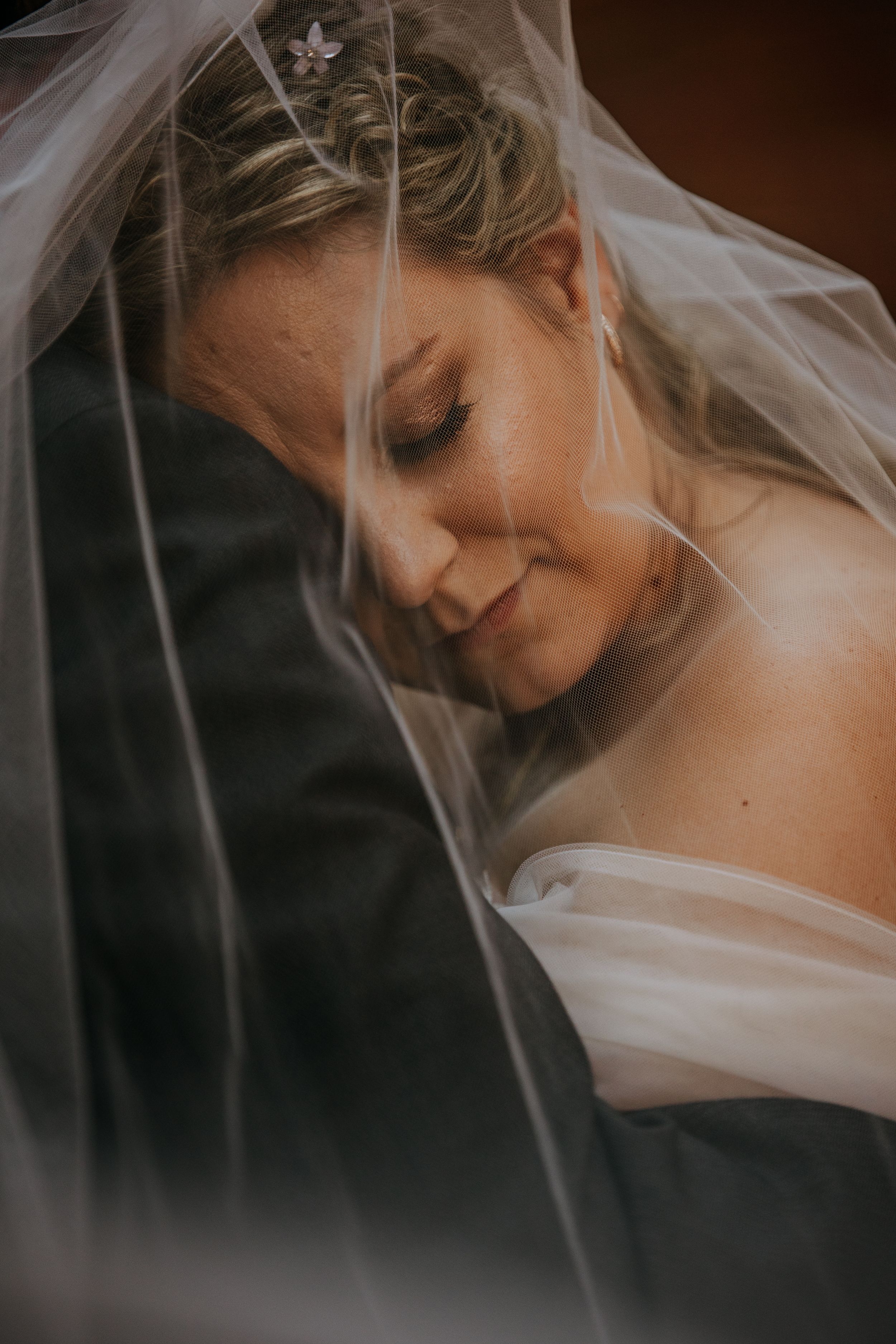 A soft and romantic bridal portrait through delicate white veil with elegant makeup and hair styling.