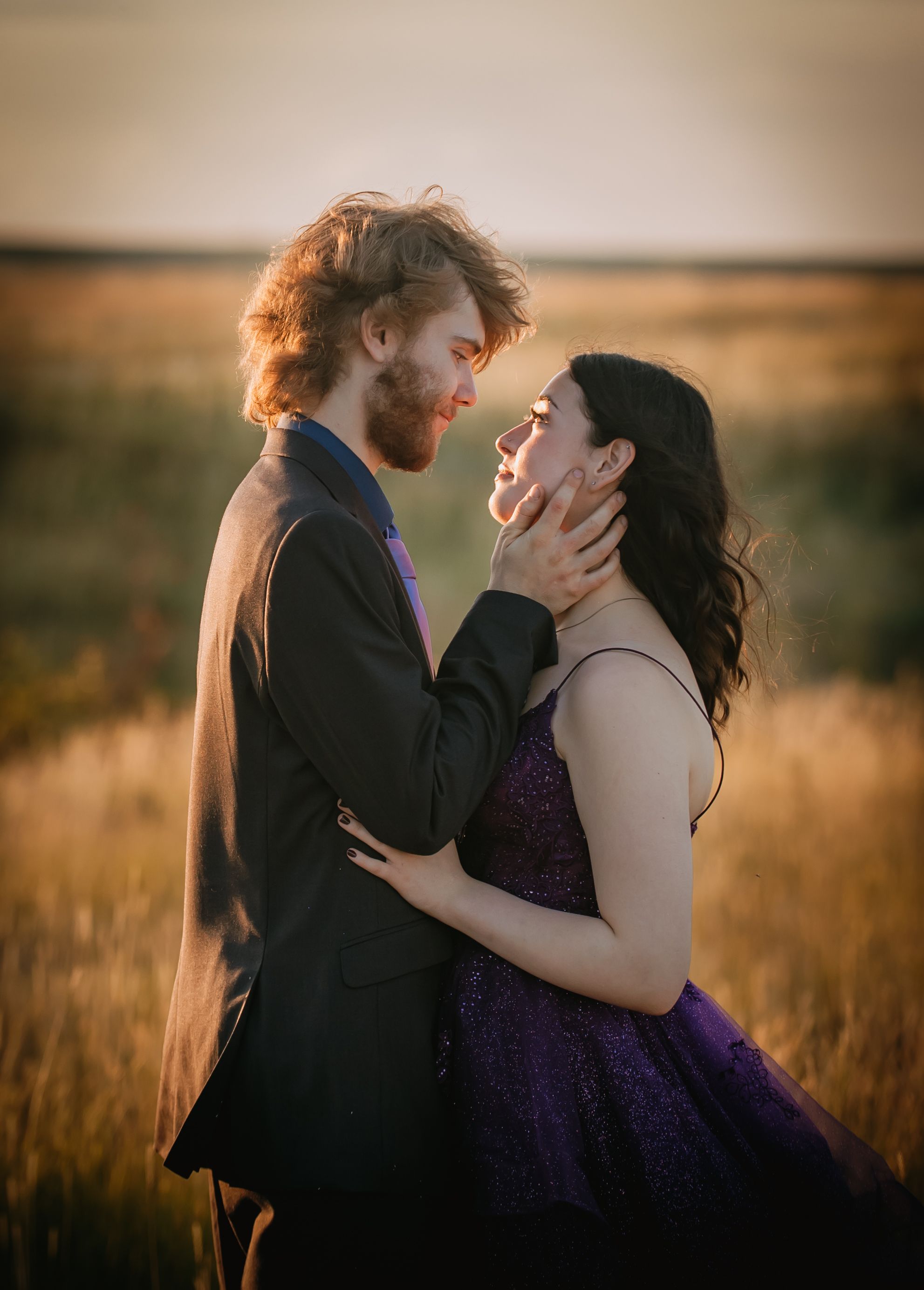 A romantic couple embraces in a golden wheat field at sunset creating a dreamy silhouette against the warm sky.