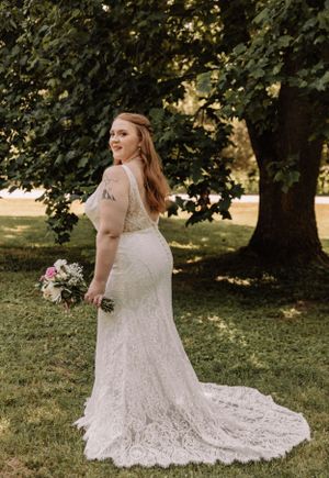 A stunning lace wedding gown with a flowing train displayed in an outdoor garden setting.