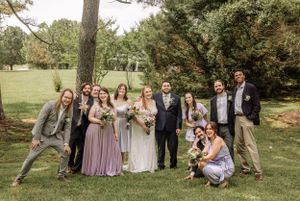 Bridal party gathers under tall trees for casual outdoor portraits in natural lighting.