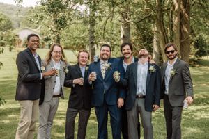 Groomsmen share authentic laughter during informal group photos in park setting.