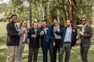 Wedding party enjoys candid moment while taking photos in natural outdoor environment.