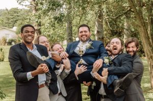 Wedding party members share lighthearted moments during an outdoor photo session in nature.