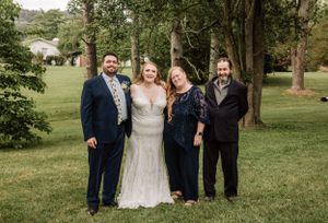 Wedding group portrait session in a natural outdoor setting with lush greenery.