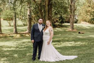 A couple poses for their wedding photos in a sunlit wooded area.