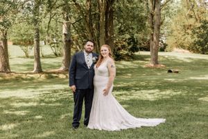 A couple smiles at the camera during their outdoor wedding photoshoot.