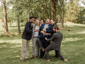 Groomsmen sharing laughs and casual moments during outdoor wedding photography.