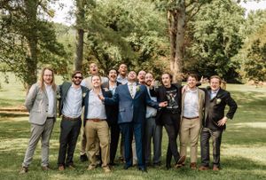 Large wedding party group photo with guests lined up outdoors in formal attire.