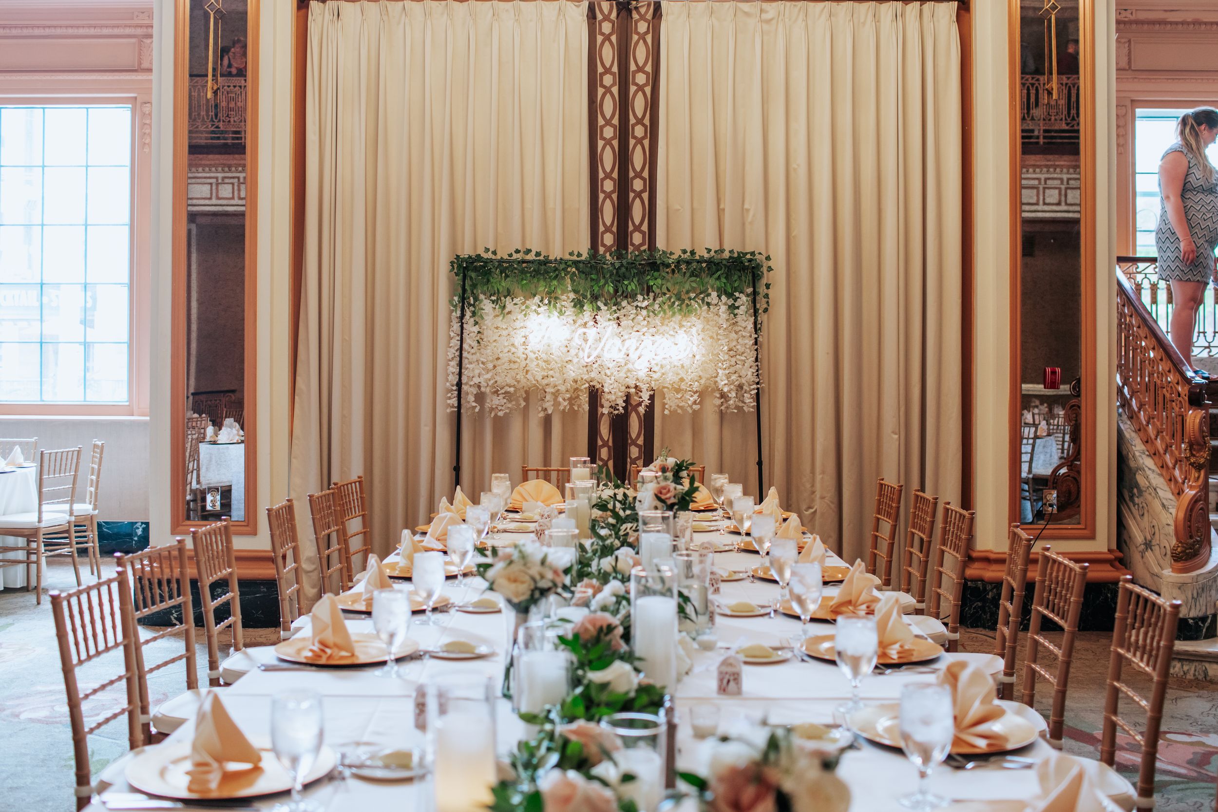 A panoramic view of an elegant wedding reception venue with white tablecloths and rustic wooden chairs.