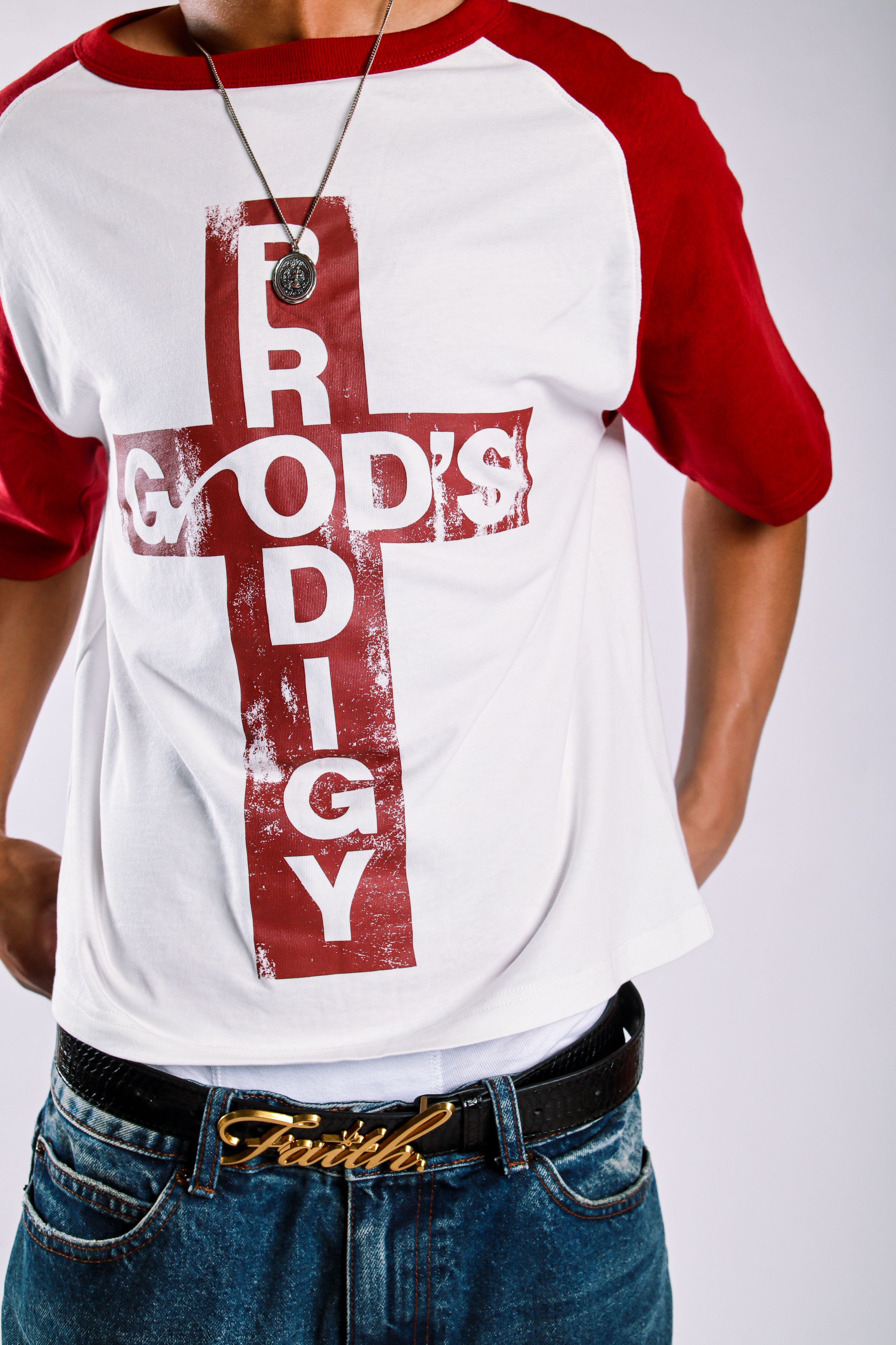 White and red raglan tee with God's Prodigy cross graphic, worn with Faith belt buckle jeans and chain necklace.